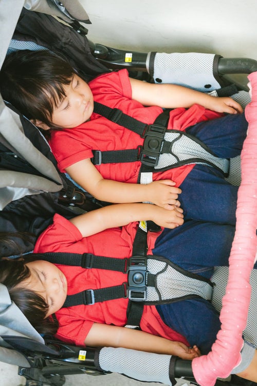 ベビーカーの上でぐっすり眠る双子の女児の写真