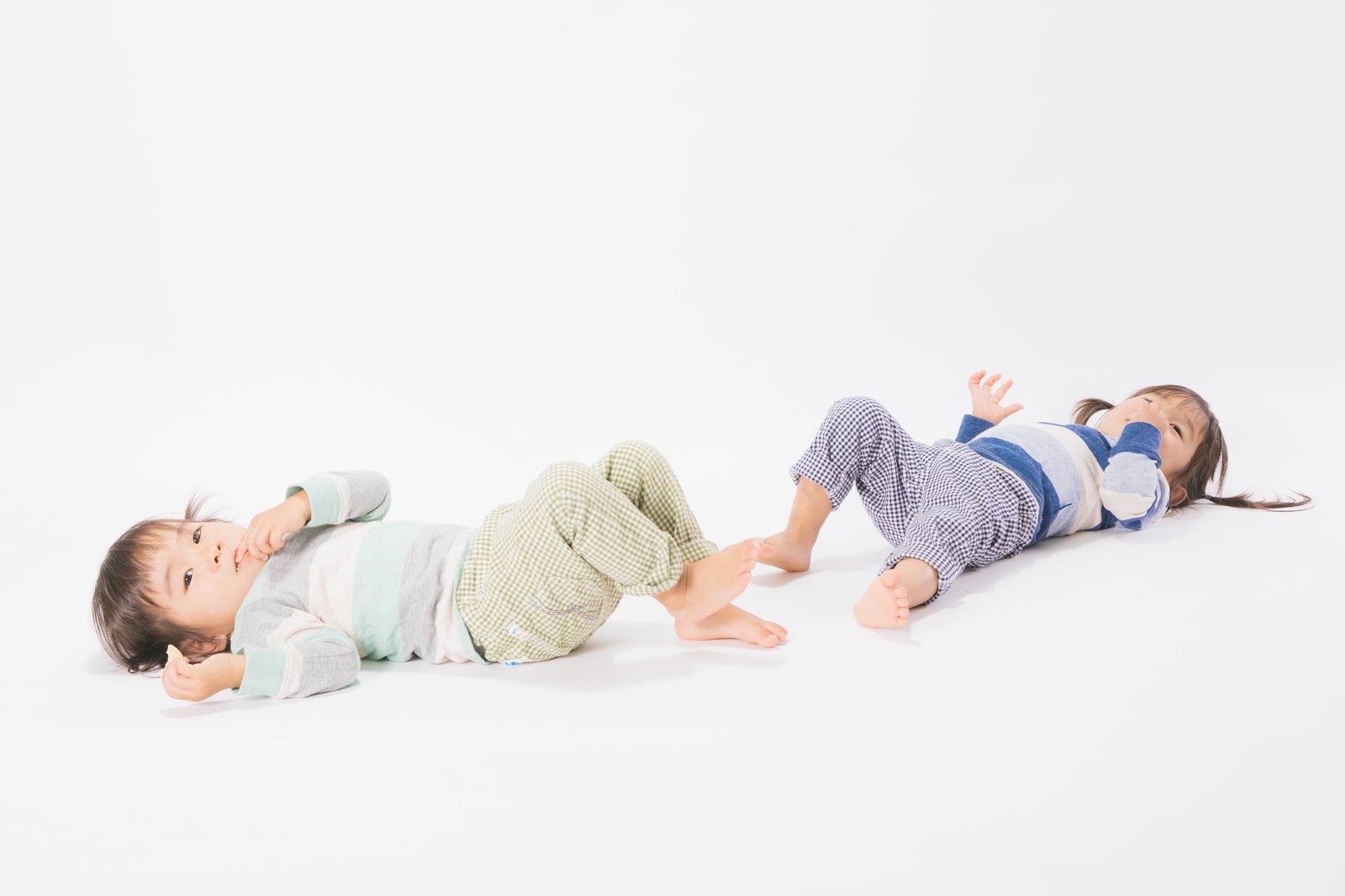 「寝そべる双子女児」の写真［モデル：あおみどり］