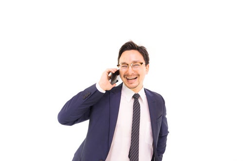 電話しながら笑顔になるドイツ人ハーフの写真