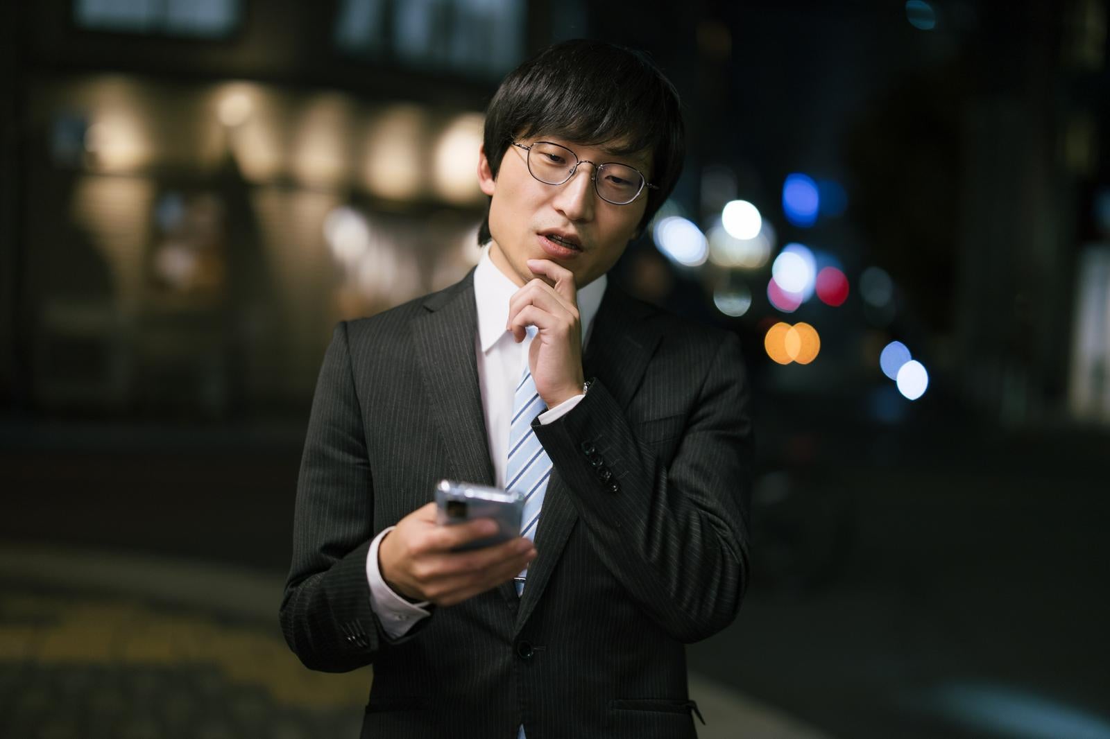 「屋外でスマートフォンをチェックする男性」の写真［モデル：あづま］