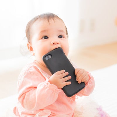 スマートフォンを口に入れてしまう赤ちゃんの写真