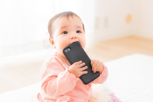 スマートフォンを口に入れてしまう赤ちゃんの写真