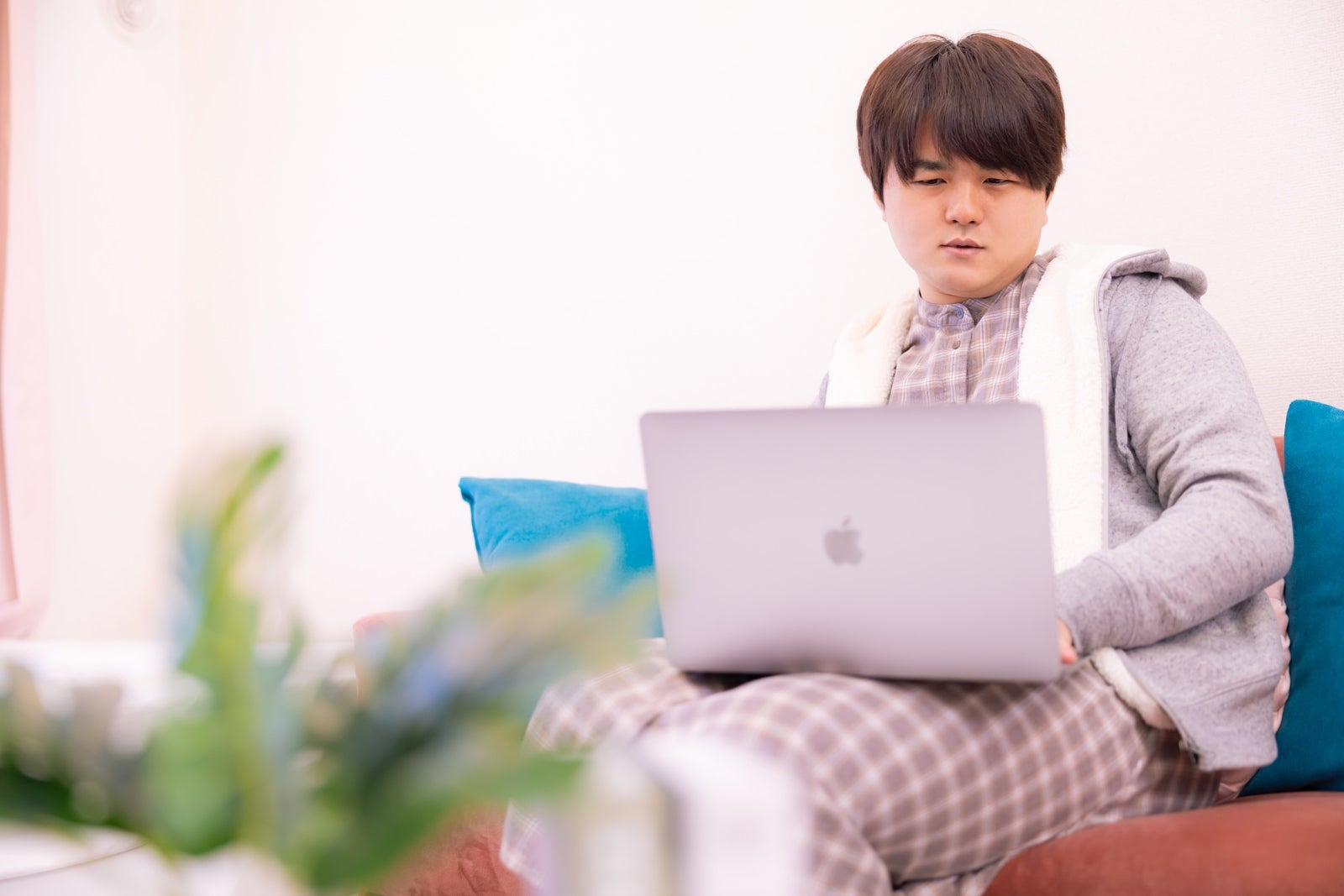 「膝の上にノートパソコンを乗せてネット検索する男性」の写真［モデル：はしも。］