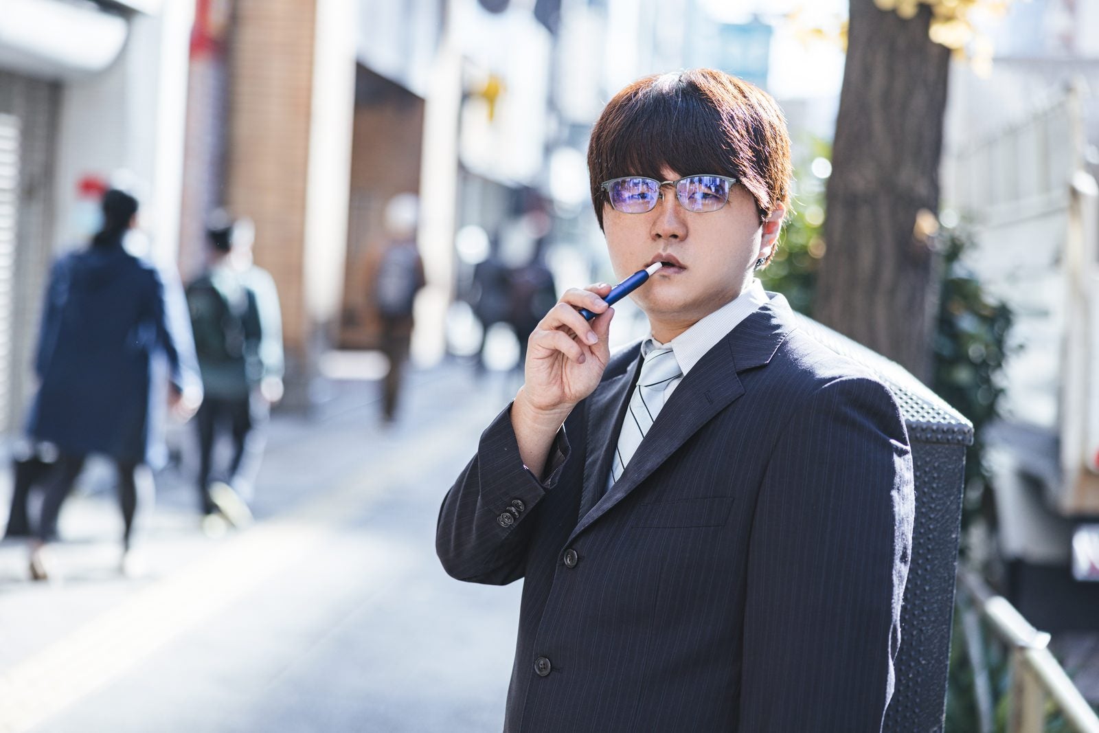 「「ここで煙草は吸わないでもらえますか」と言われて不機嫌そうな会社員」の写真［モデル：はしも。］