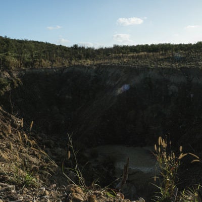 荒れ地にぽっかりと口を開けている硫黄島旧噴火口（ミリオンダラーホール）の写真