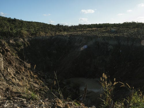 荒れ地にぽっかりと口を開けている硫黄島旧噴火口（ミリオンダラーホール）の写真