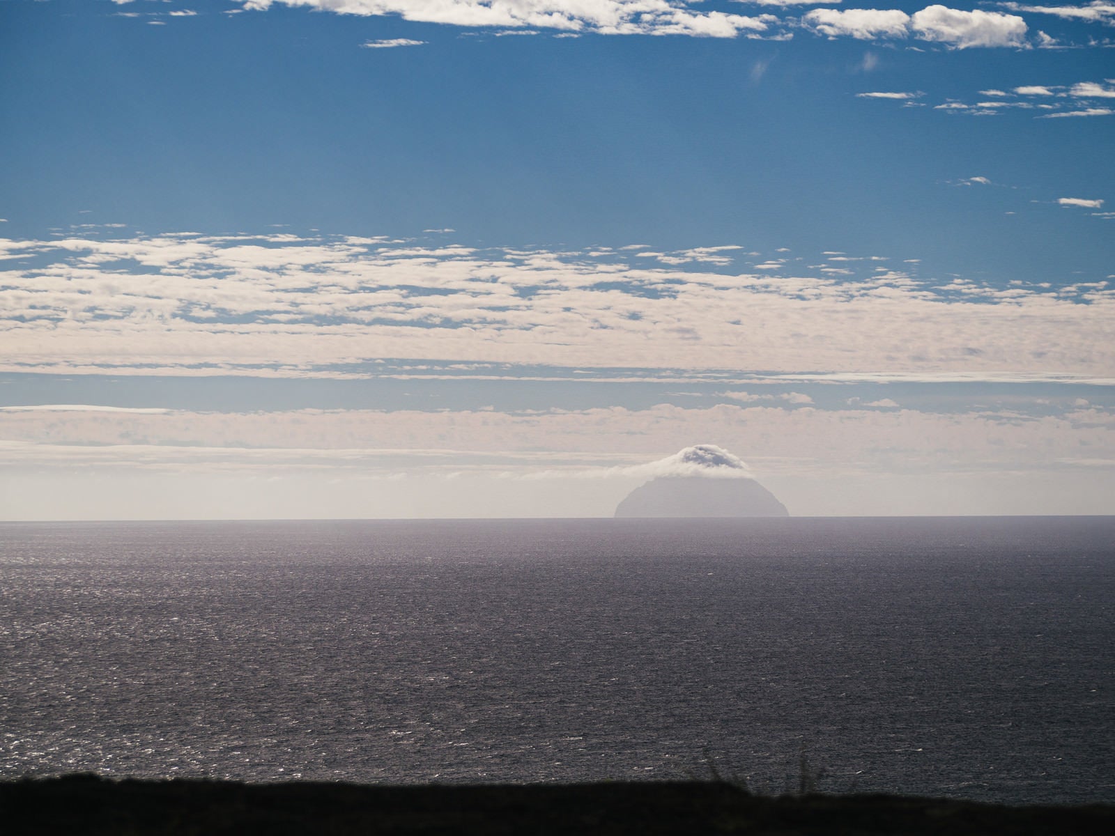 「摺鉢山から霞んで見える雲をまとった南硫黄島」の写真