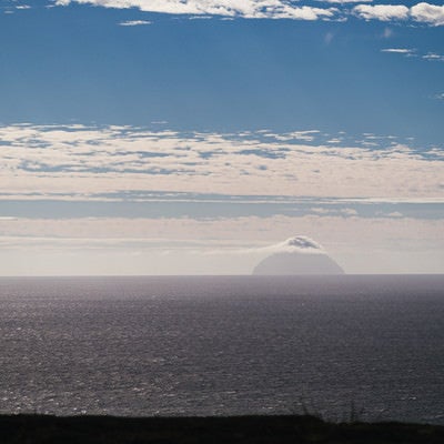 摺鉢山から霞んで見える雲をまとった南硫黄島の写真