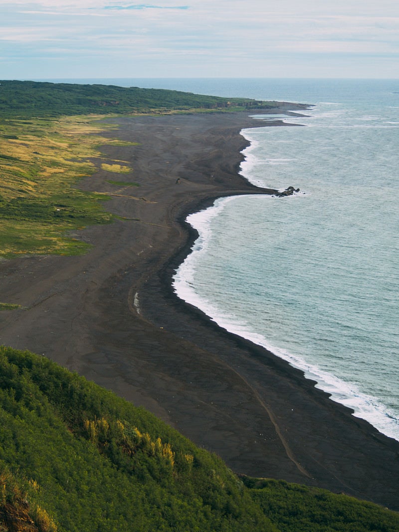 摺鉢山から見える黒々とした砂浜の上陸海岸（二ツ根浜（手前）と翁浜（奥））の写真