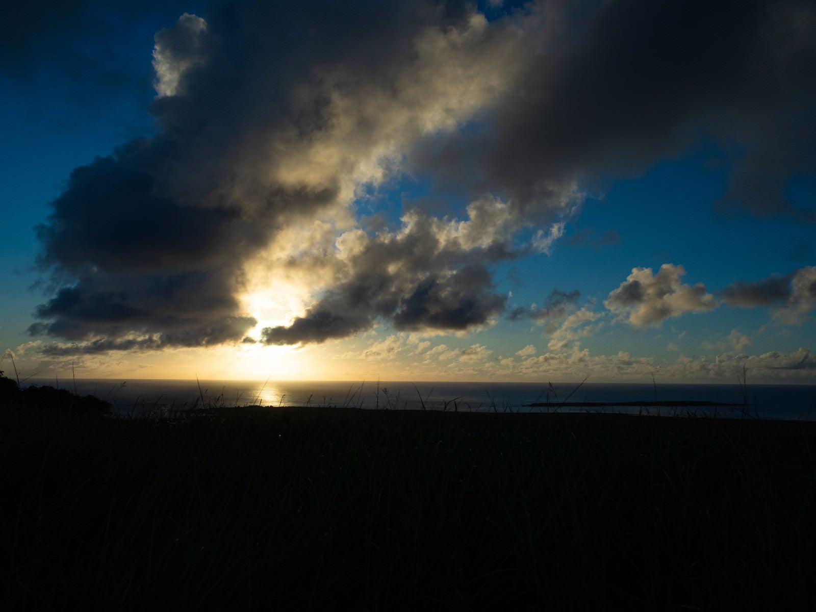 「夕陽に照らされる遠くに見える海岸の釜岩と細長い姿が海にうかぶ監獄岩」の写真