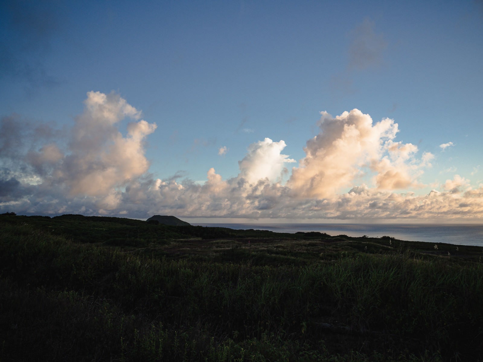 「摺鉢山と千鳥ヶ浜の向うに見える夕陽に輝く雲」の写真