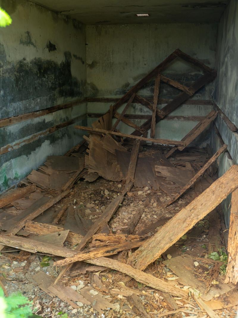 木片がバラバラと散らばるコンクリート建造物内部の写真