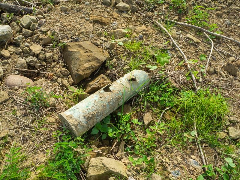 瓦礫や岩と共に地面に転がる砲弾薬莢の写真