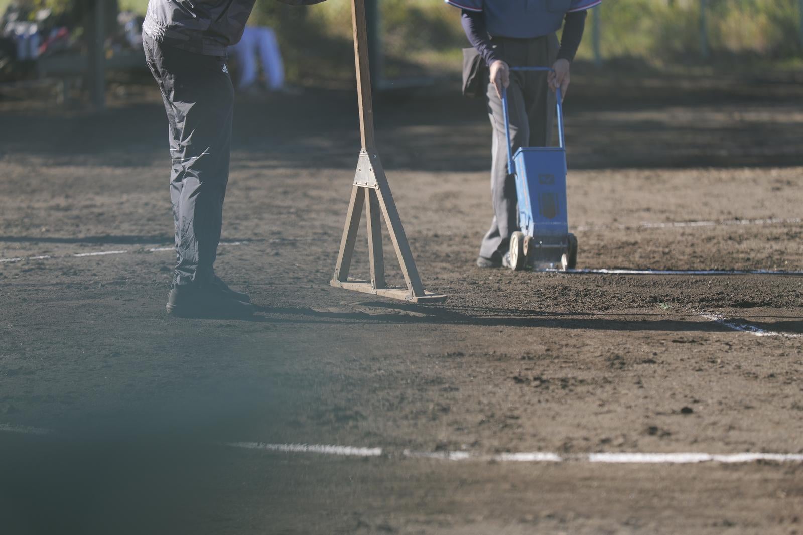 トンボを使ってグラウンドの土を整地している作業員の足元