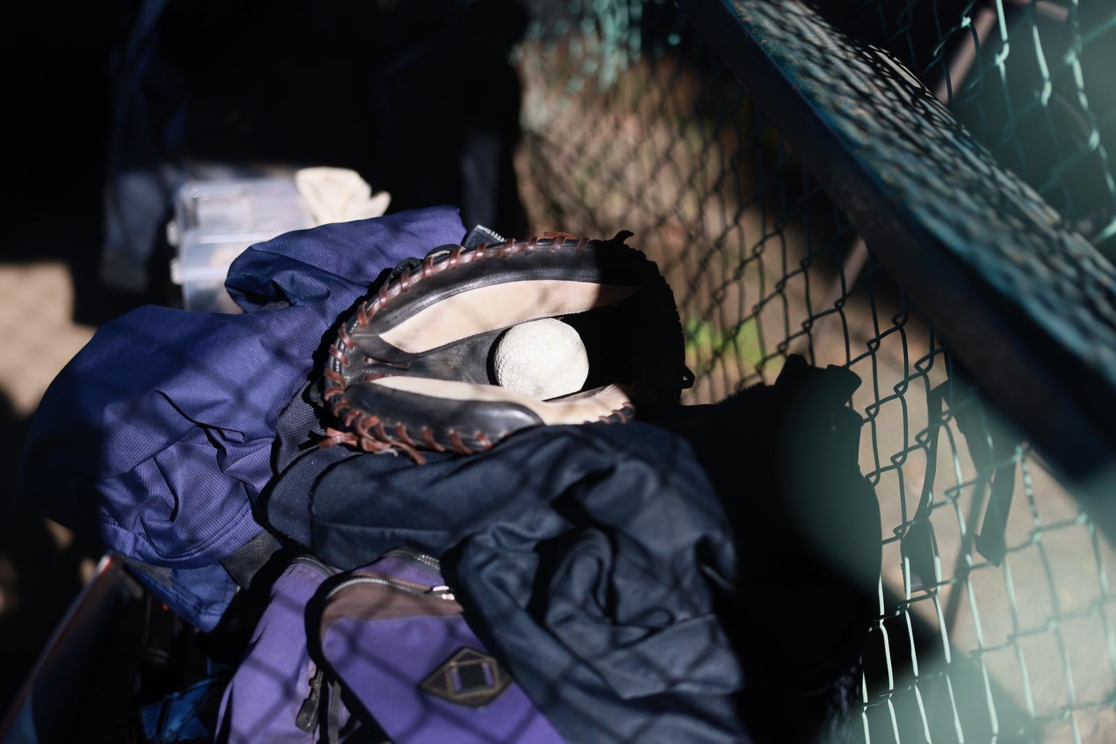 ベンチに置かれたキャッチャーミットと野球ボール、紺色のジャケット