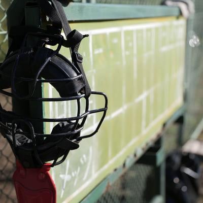 金網フェンスに掛けられた黒いキャッチャーマスクの写真