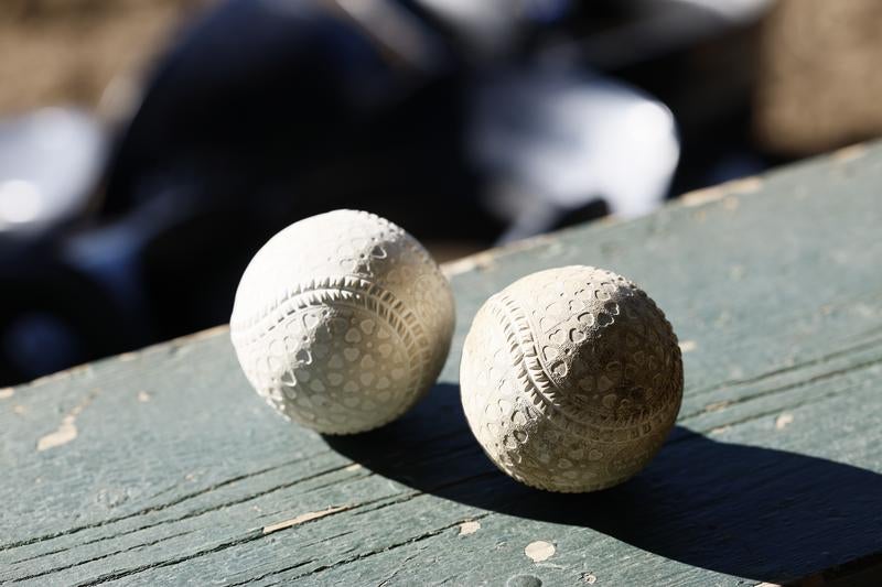木製ベンチに置かれた2個の野球ボールの写真