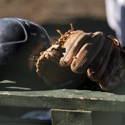 ベンチに置かれた野球ヘルメットとグローブの写真