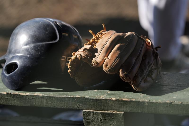 ベンチに置かれた野球ヘルメットとグローブの写真