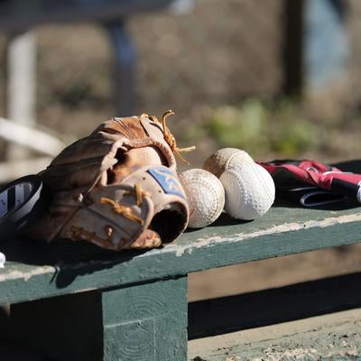 緑色のベンチに置かれた野球グローブと白いボールの写真