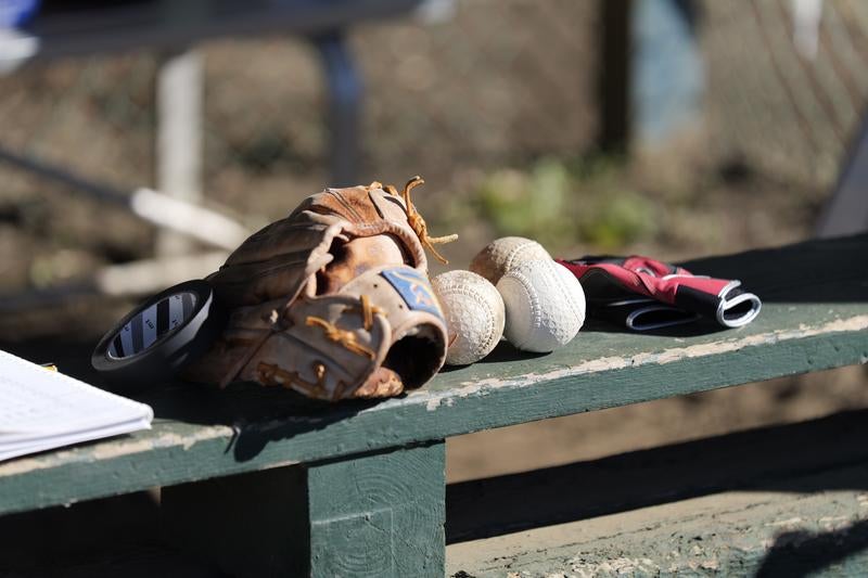 緑色のベンチに置かれた野球グローブと白いボールの写真