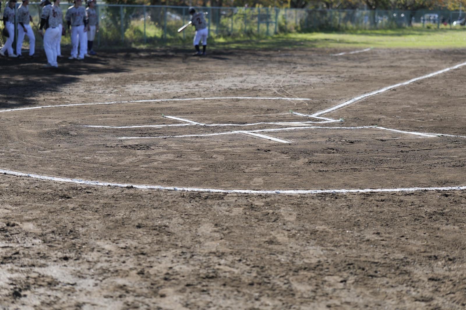 土のグラウンドに白線で描かれた野球のホームベース周辺