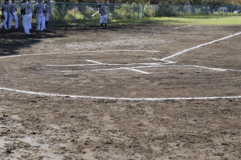 白線で区切られた野球場のホームベース周辺と土のグラウンドの写真