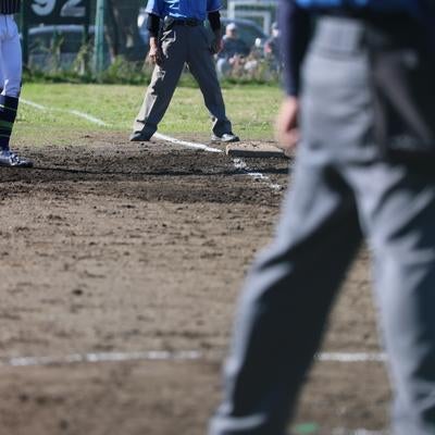 審判と選手が写る土のグラウンドでの野球の試合の写真