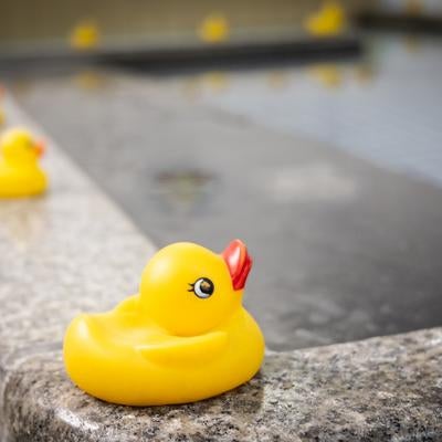 浴槽の縁に並ぶアヒルのおもちゃの写真