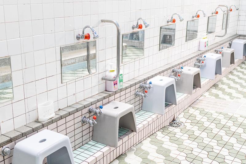 銭湯の洗い場に並ぶ蛇口と風呂椅子