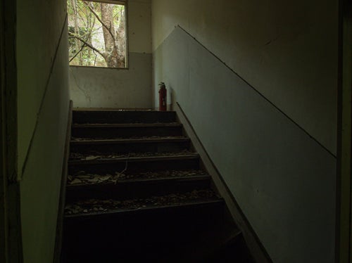廃墟の階段とその上にある消化器の写真