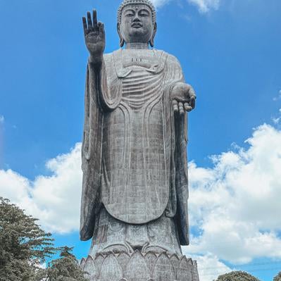 青空と雲を背景に聳える巨大な牛久大仏の立像の写真