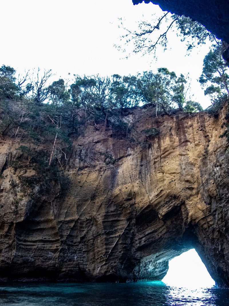 「水面に口を開ける龍宮窟と岩肌」の写真