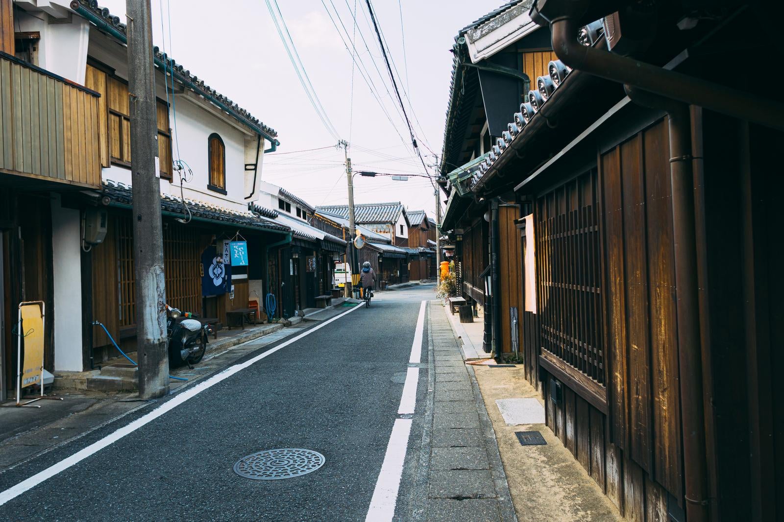 湯浅町の木造家屋が並ぶ細い路地と、奥に自転車で進む人の後ろ姿