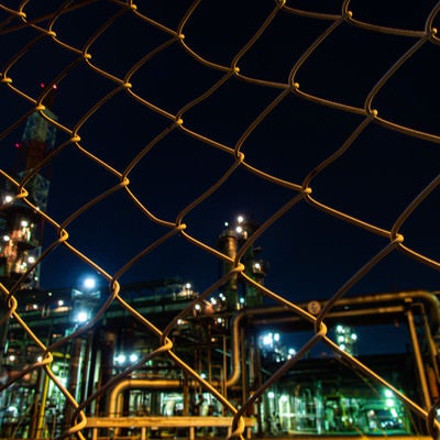 フェンス越しの工場夜景の写真