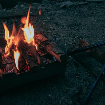 キャンプファイヤーの炎とトングの写真