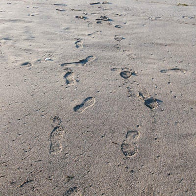 濡れた砂浜に残る靴跡の写真