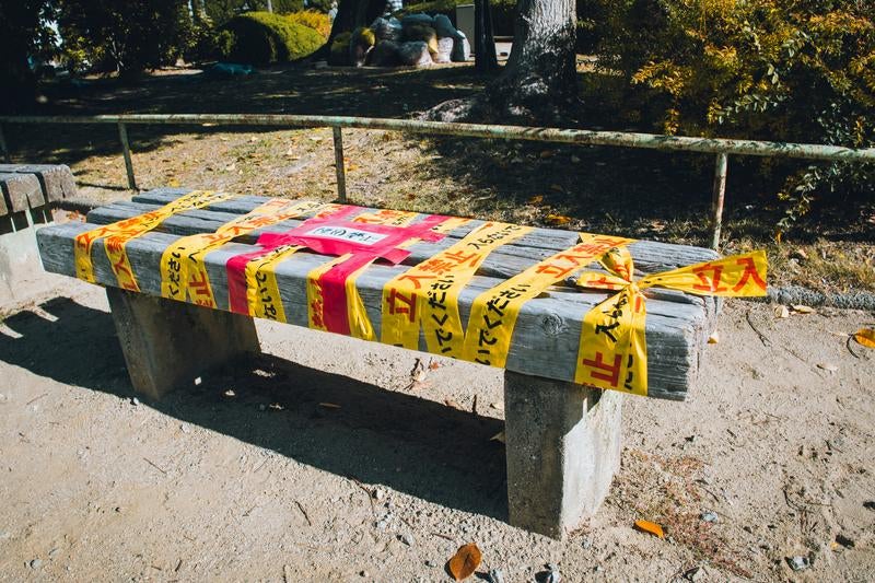 立入禁止テープが巻かれたベンチの写真