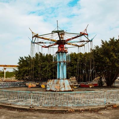 廃墟となった遊園地の錆びた回転ブランコの写真