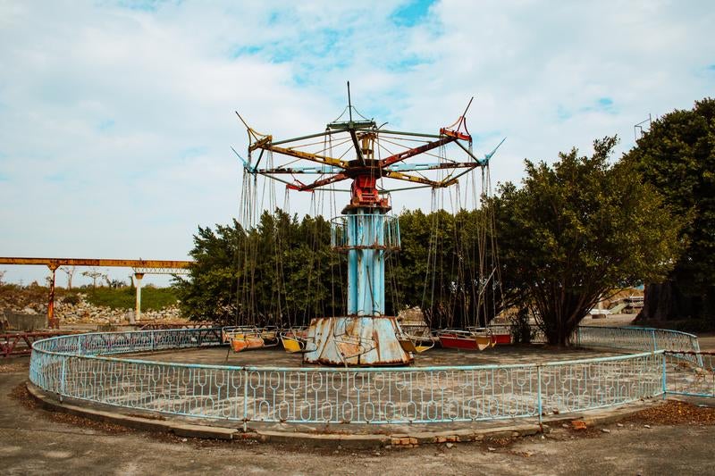 廃墟となった遊園地の錆びた回転ブランコの写真