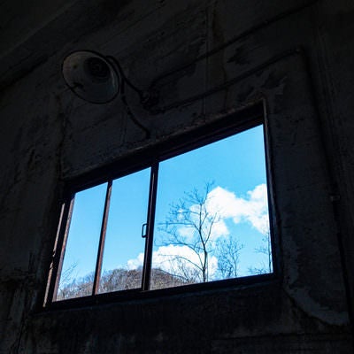 廃墟の窓から見える青空の写真