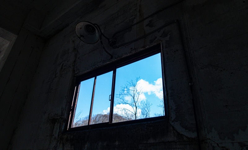 廃墟の窓から見える青空の写真