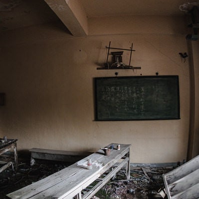 朽ちた廃屋と黒板の写真