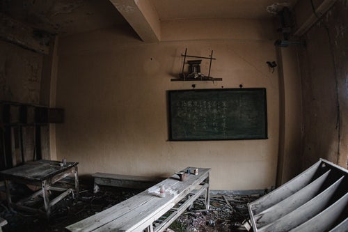 朽ちた廃屋と黒板の写真