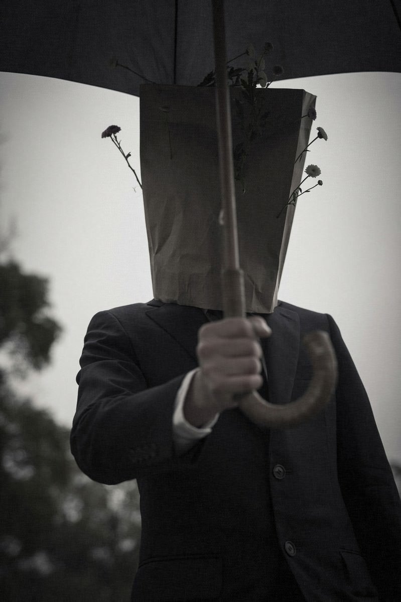 「傘を手渡す紙袋紳士」の写真