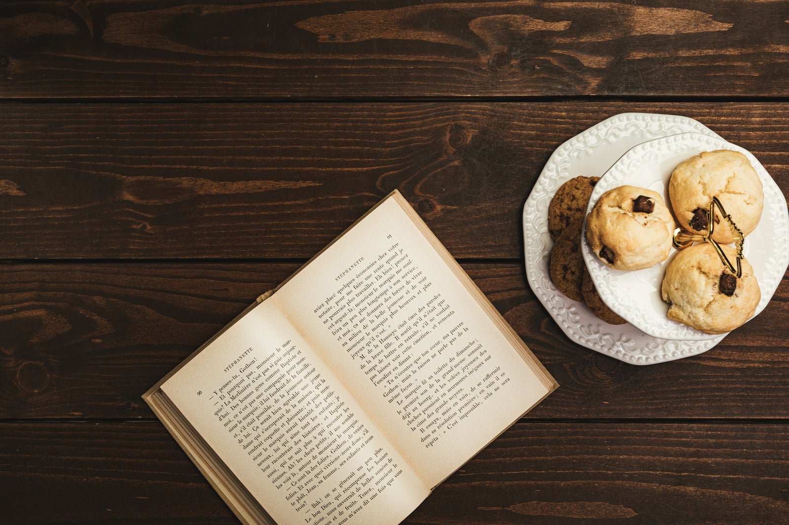「卓上に置かれた読みかけの洋書とクッキー」の写真