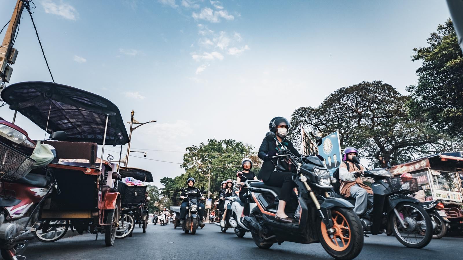「東南アジアの典型的な交通渋滞の中でヘルメットを着用してバイクに乗る現地の人々」の写真