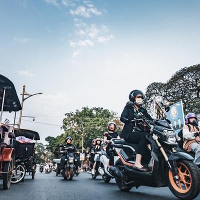 東南アジアの典型的な交通渋滞の中でヘルメットを着用してバイクに乗る現地の人々の写真