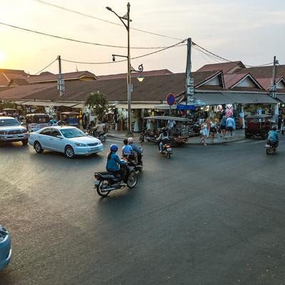 カンボジアの地方都市を走るバイクと車の風景（シェムリアップ）の写真