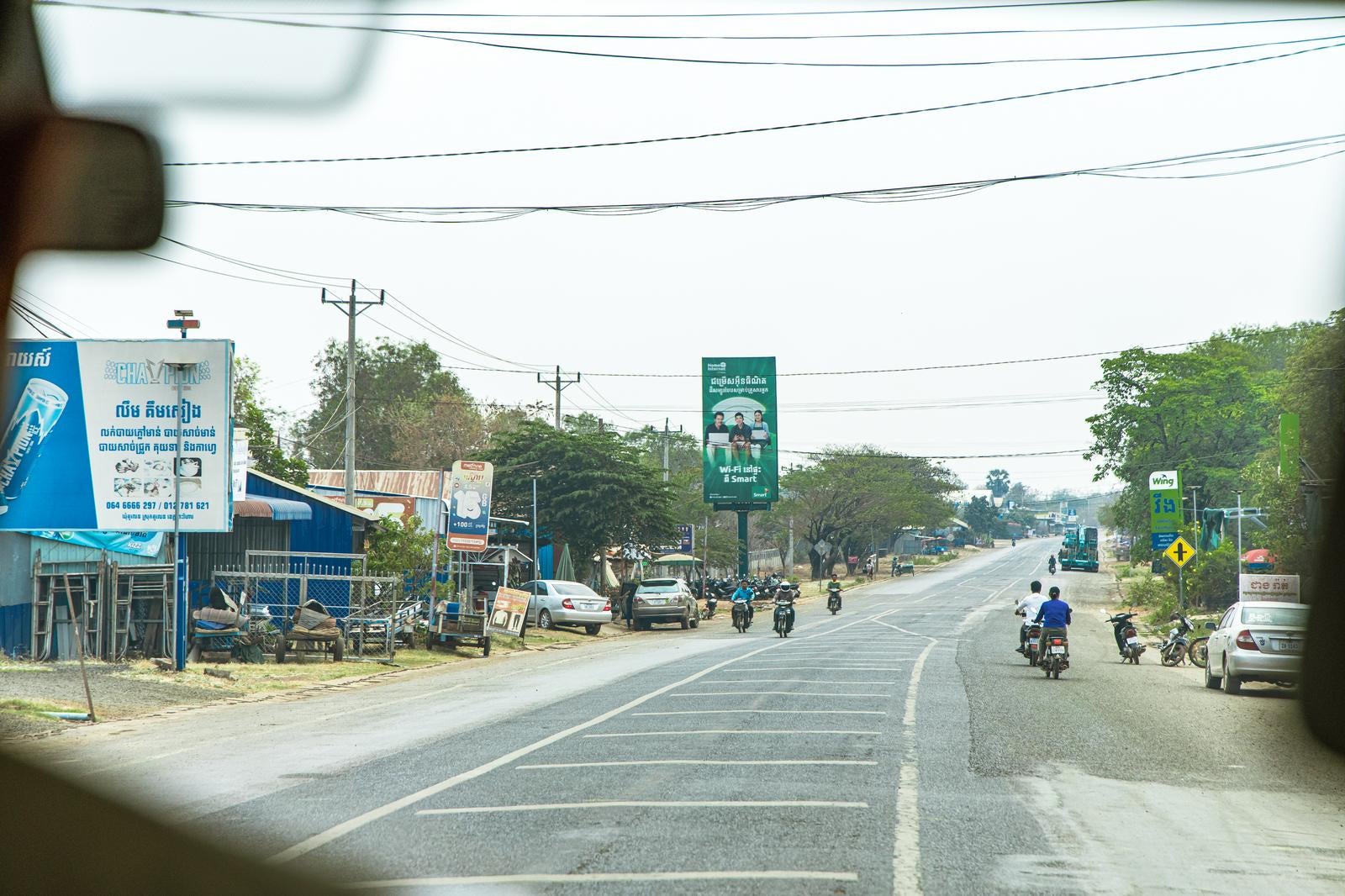 「カンボジアの国道沿いに広がる商店街と電線が張り巡らされた街並み」の写真